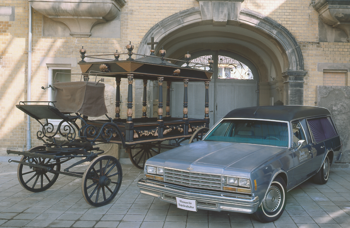 Bestattungsfahrzeug Chevrolet Impala, 1978 und Leichenkutsche (Marburg), um 1880, Foto: Museum für Sepulkralkultur
